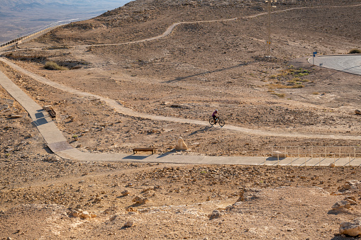 Mitzpe Ramon, Israel - August 5, 2023; A cyclist rides on a path above the Ramon crater in the town of Mitzpe Ramon.