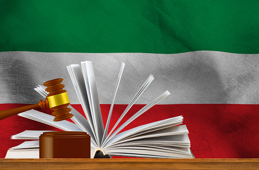 Judicial gavel on the background of an open book and the flag of Iran. 3D image