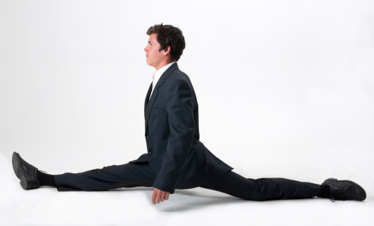 Young and good-looking businessman does the splits with ease against a white background