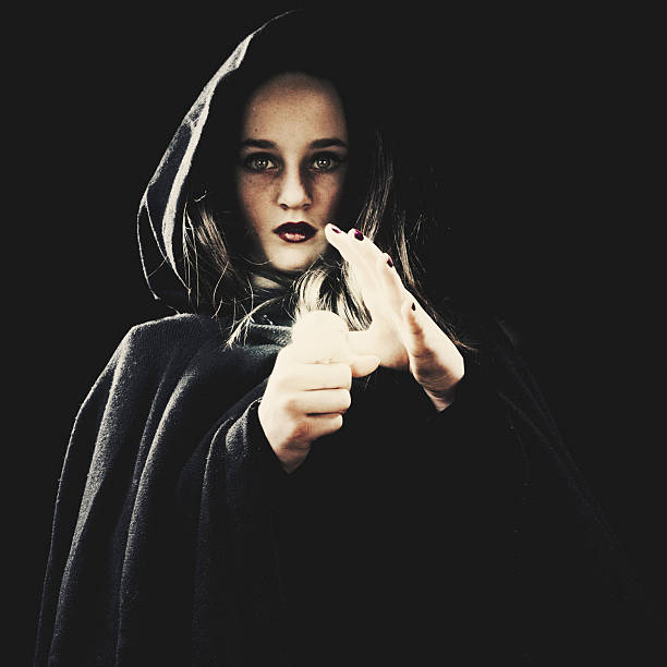 Spooky young girl wearing a hood reading the future in a small crystal ball.