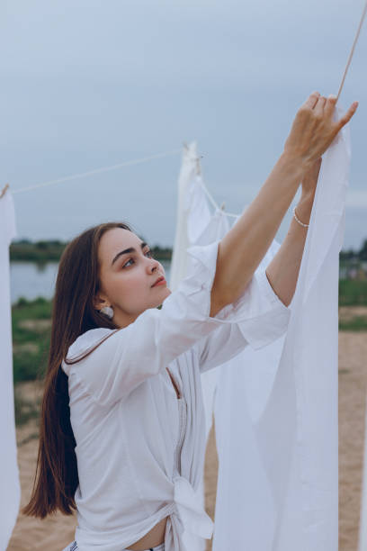 istock Woman drying sheets on clothesline in countryside 1602974338