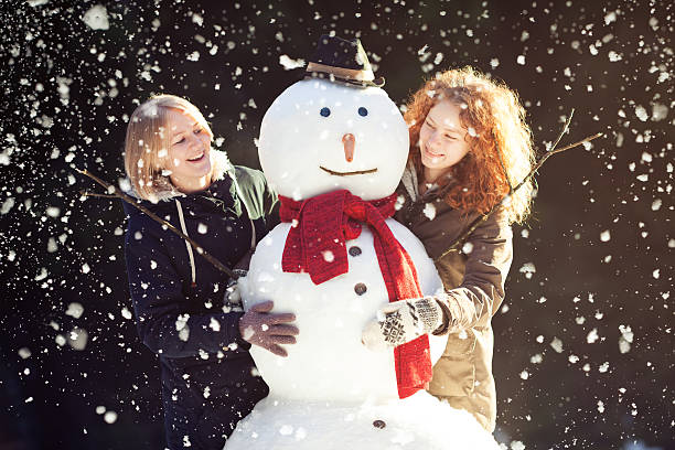 istock Two young women hugging snowman 160298597