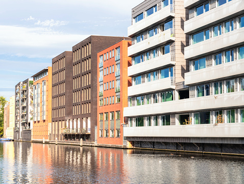 A long row of modern canal-side buildings in Amsterdam, Netherlands.