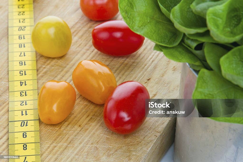 Salad, tomatos and measurement tape Salad, tomatos and measurement tape - diet and healthy eating; weight loss concept Centimeter Stock Photo
