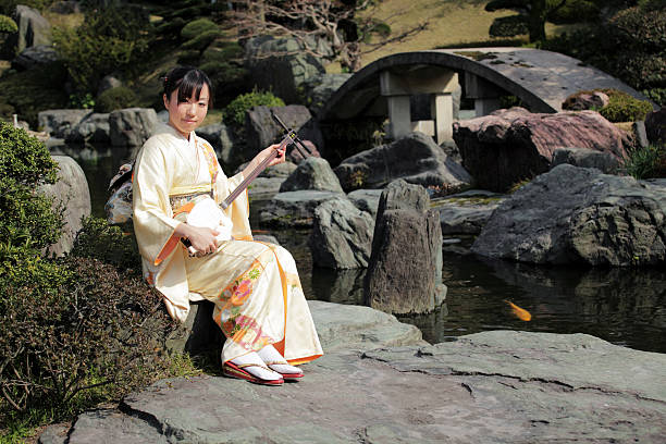 Woman playing shamisen in Japanese garden stock photo