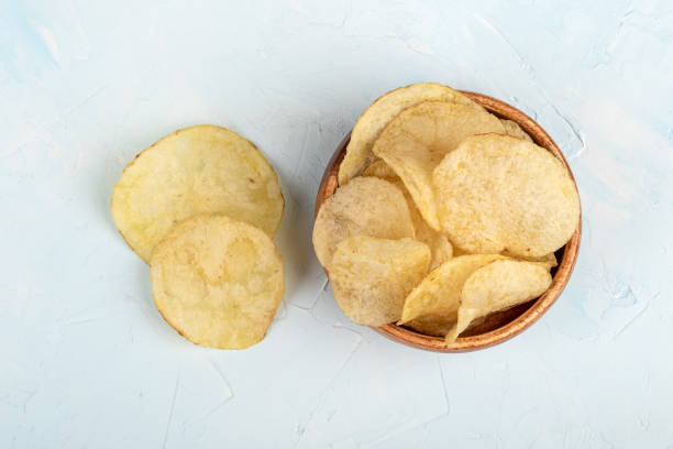 istock Top view of delicious crispy potato chips on blue background. 1603027164