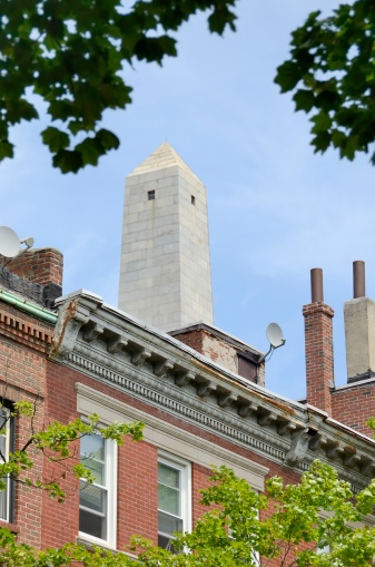 Low angle view of Bunker Hill Monument in Boston, Massachusetts with residential architecture in the foreground.