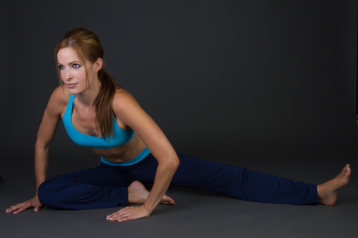 fit woman doing stretching exercises on black background