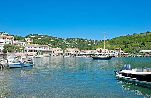 Tranquil harbour of Agios San Stefanos, Corfu, Greece. The Island of Corfu, Greece. Corfu, or Korkyra, lies to the west of the Greek and Albanian mainland and separates the Adriatic from the Ionian Seas. Largely formed from Limestone, the island measuring some thirty miles by 18 miles is now a tourist destination, known for its beaches, climate and olives. Medieval castles and ancient ruins chart the military history of the island back to ancient Greek mythology.