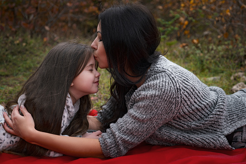 Mom and her 4 years old daughter spending weekend, picnic in the autumn forest together. Mother and child relations.