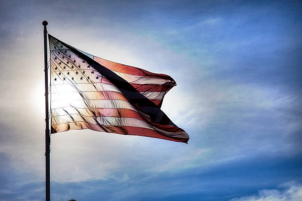 US Flag Fluttering in Backlit Blue Sky Symbolizing Government Transparency stock photo