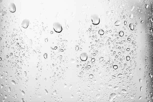 Water drops texture Water droplets on glass in front of a white background.  Various sizes of water droplets from large to very small rest on the front of a glass.  The droplets near the top of the image are larger and more visible than the droplets near the bottom and to the sides.  The larger droplets have slight shadowing to them which gives the drops an added depth and texture.  The very top of the image has no droplets.  The white background is a gradient with darker edges on the sides and an almost black edge on the right. condensation stock pictures, royalty-free photos & images