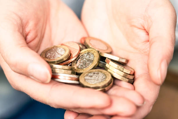 holding a collection of british coins - women savings uk coin imagens e fotografias de stock