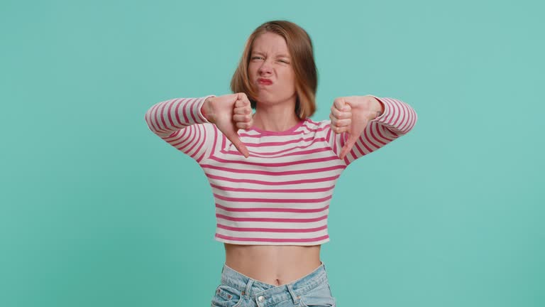 Upset attractive young woman girl showing thumbs down sign gesture, disapproval dissatisfied dislike