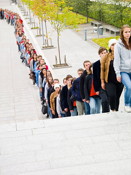 menschen warten in long line - länge stock-fotos und bilder