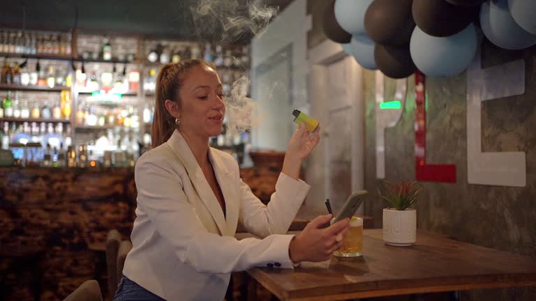 Woman enjoying disposable vape cigarette at the bar