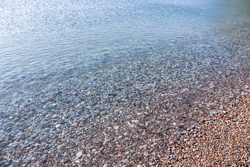 Clear calm sea waters meet pebble beach closeup as natural background