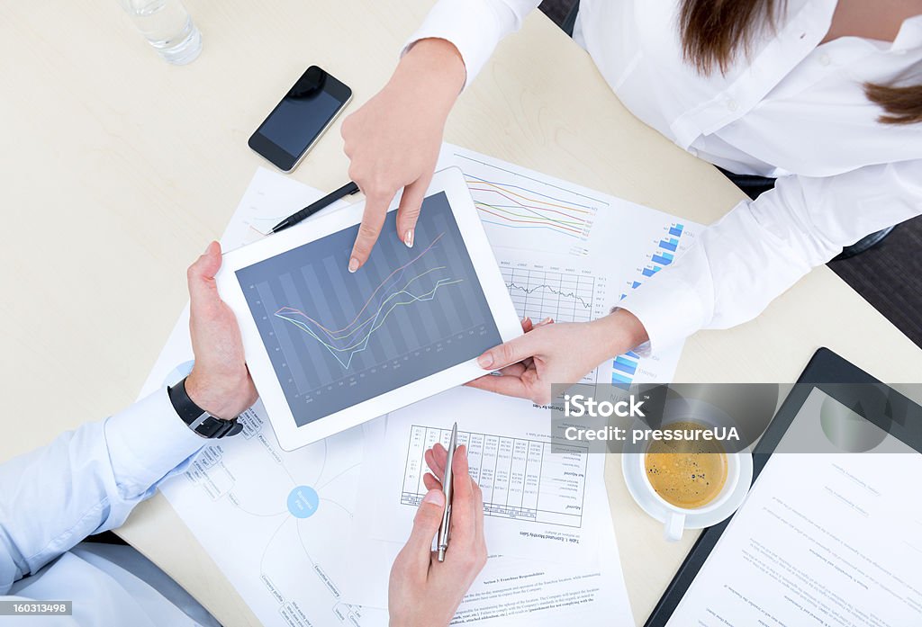 Discussion of strategy with a financial analyst Businessman discussing with financial analyst business development strategy project and using modern digital tablet with chart on a screen. Top view photoshoot. Financial Analyst Stock Photo