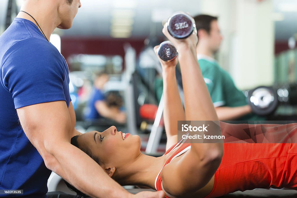 Mujer con pesas individuales dumb bells y su entrenador de ejercicios de gimnasio - Foto de stock de Actividad libre de derechos