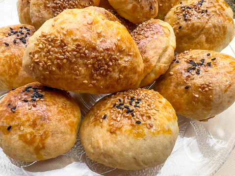 bakery, delicious small savory bread buns with seed and sesame on plate for breakfast or tea time snack. homemade buns or rolls on plate. handmade or homemade local bakery food concept