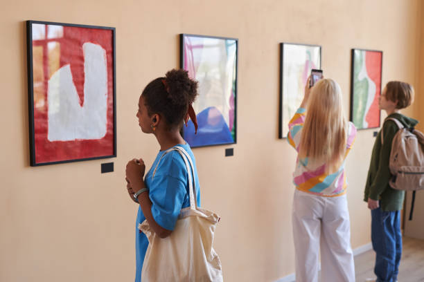 разнообразная группа подростков, смотрящих на абстрактное искусство в художественной галерее - child art people contemporary стоковые фото и изображения
