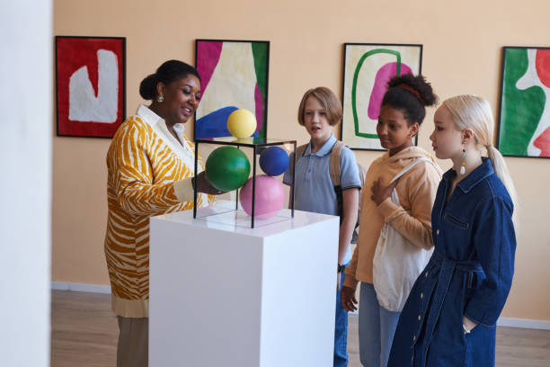teenagers listening to teacher or tour guide in modern art gallery - museum child art museum art imagens e fotografias de stock