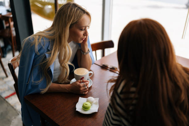 istock Closeup high-angle view of two happy charming girlfriends using mobile phone sitting at the cafe and looking to screen. Beautiful best female friends 1603195338