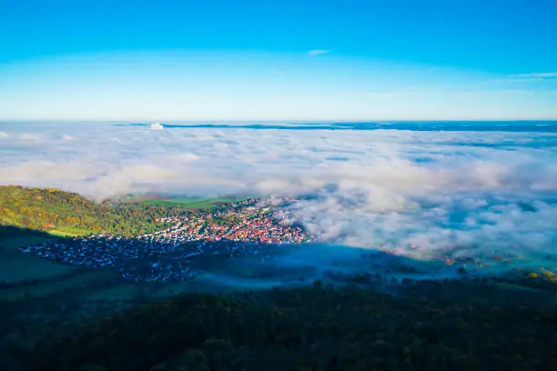 Germany, Bissingen an der teck village houses aerial panorama drone view above buildings under foggy ocean of clouds and fog at sunrise