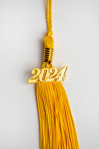 A class of 2024 charm on a yellow tassel on a white background.