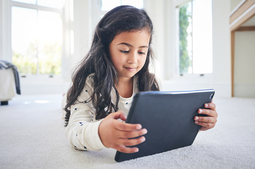 Young girl, tablet and game app or cartoon streaming online with internet, elearning and relax on carpet in house. Watch animation film, female kid at home and website, entertainment and subscription