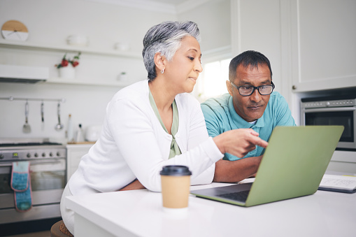 Mature couple, laptop and pointing for internet connection, communication or social media post. A man and woman talking at home while together for online streaming, search or email with technology