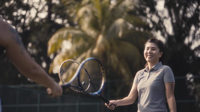 Asian Chinese female Tennis players greeting touching tennis racket over tennis net with his opponent before game begin