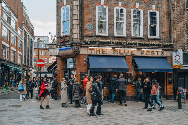 London, UK - April 13, 2023: People walking past The Blue Posts pub in Soho, an area of London famous for LGBTQ+ bars, restaurants and clubs.
