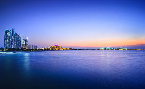 Beautiful view of a city and water in Abu Dhabi Panoramic view over the Persian Gulf on Abu´s Dhabi´s skyline, with the landmarks Etihad Towers, the Emirates Palace and ongoing offshore constructions on the nearby island at dusk. abu dhabi stock pictures, royalty-free photos & images