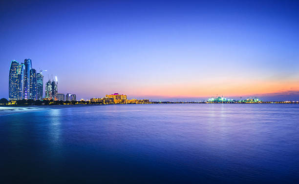 Beautiful view of a city and water in Abu Dhabi Panoramic view over the Persian Gulf on Abu´s Dhabi´s skyline, with the landmarks Etihad Towers, the Emirates Palace and ongoing offshore constructions on the nearby island at dusk. corniche stock pictures, royalty-free photos & images