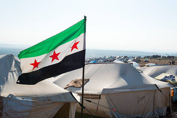 Free Syrian flag in refugee camp (Atmeh, Syria) Free Syrian flag flying inside the camp for displaced persons at Atmeh, Syria syria stock pictures, royalty-free photos & images