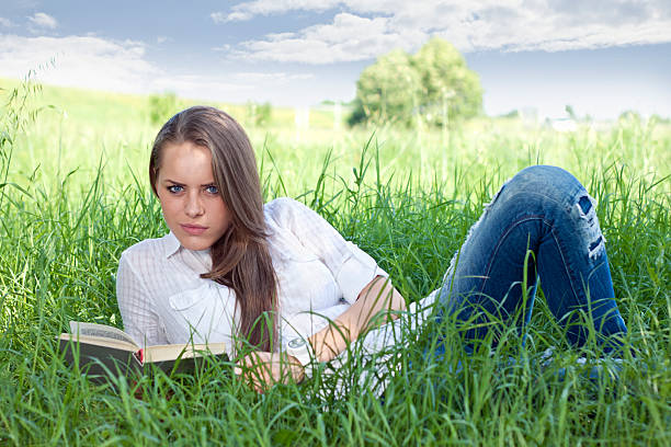 istock Pretty young woman reading a book outside 160327362