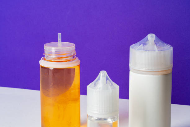 istock Electronic cigarettes liquid bottles on purple background 1603284865