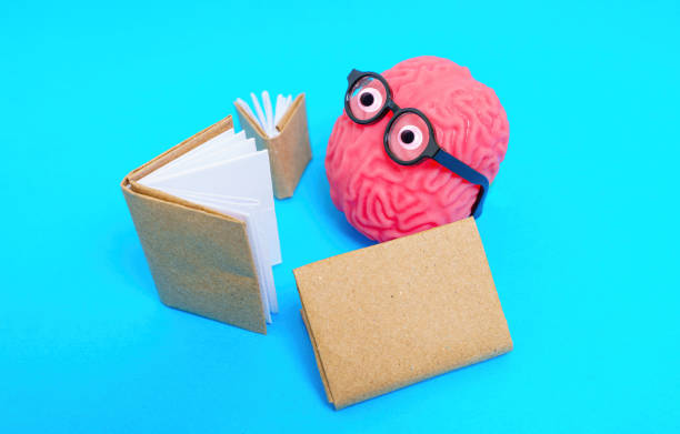 istock Human Brain Character with Googly Eyes and Glasses Reading 1603286998