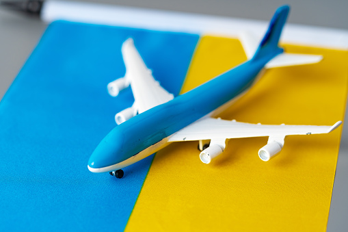Ukrainian flag and toy plane on gray background close up