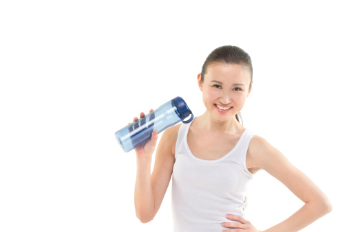 A beautiful asian woman holding a sports bottle in her hand. Photographed in studio.