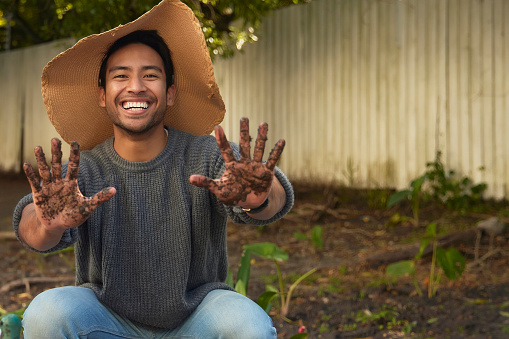 A handsome man proudly displays his dirt-streaked hands after a rewarding session of gardening. His confident smile and rugged appearance reflect a sense of fulfillment and hard work, embodying the satisfaction that comes from tending to the earth and creating something beautiful.