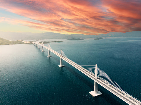 Aerial view of beautiful modern multi-span cable-stayed Peljesac Bridge over the sea in Dubrovnik-Neretva County, Croatia at sunrise with cloudy weather and storm in the background.