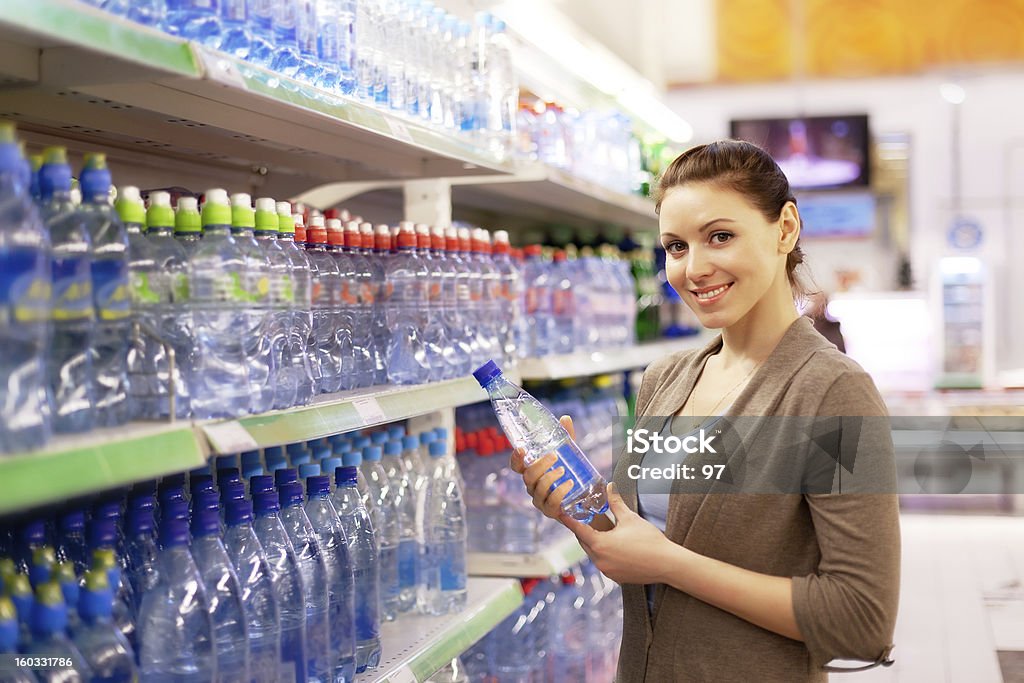 La femme achète une bouteille d'eau minérale à acheter - Photo de Acheter libre de droits