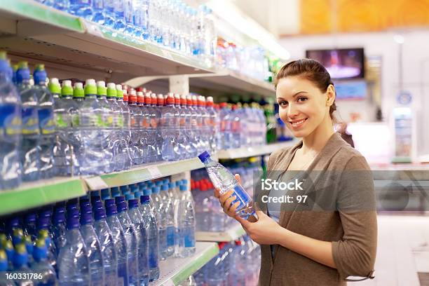 Photo libre de droit de La Femme Achète Une Bouteille Deau Minérale À Acheter banque d'images et plus d'images libres de droit de Acheter