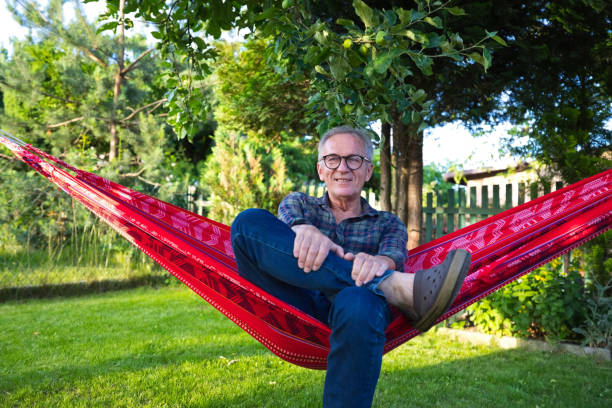 istock Senior man wearing eyeglasses sitting on hammock 1603338272
