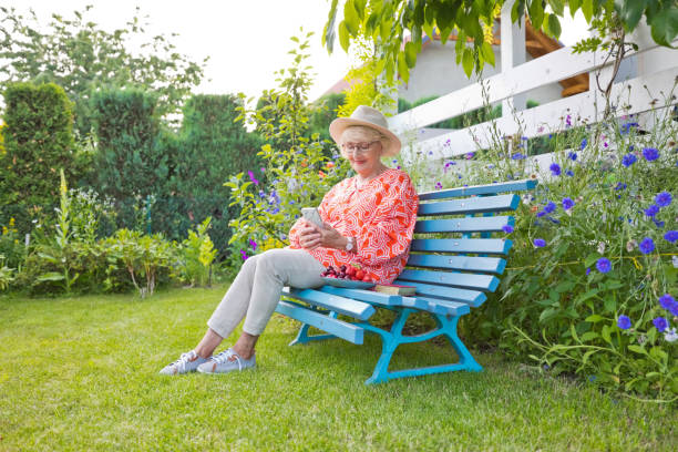 istock Smiling senior woman using phone in garden 1603340994
