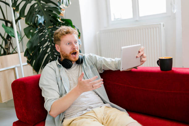 istock Mature ginger businessman drinking coffee and working on digital tablet at home 1603355806