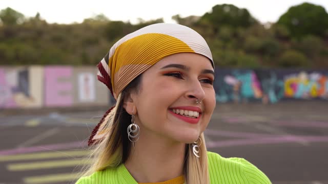 Young girl smiling on camera while wearing trendy head scarf outdoor