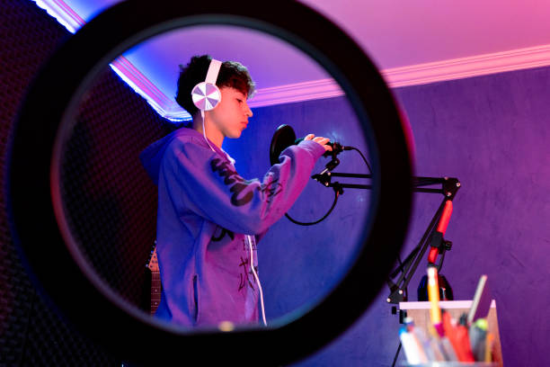 istock Young boy singing with microphone and recording music in home studio. 1603361800